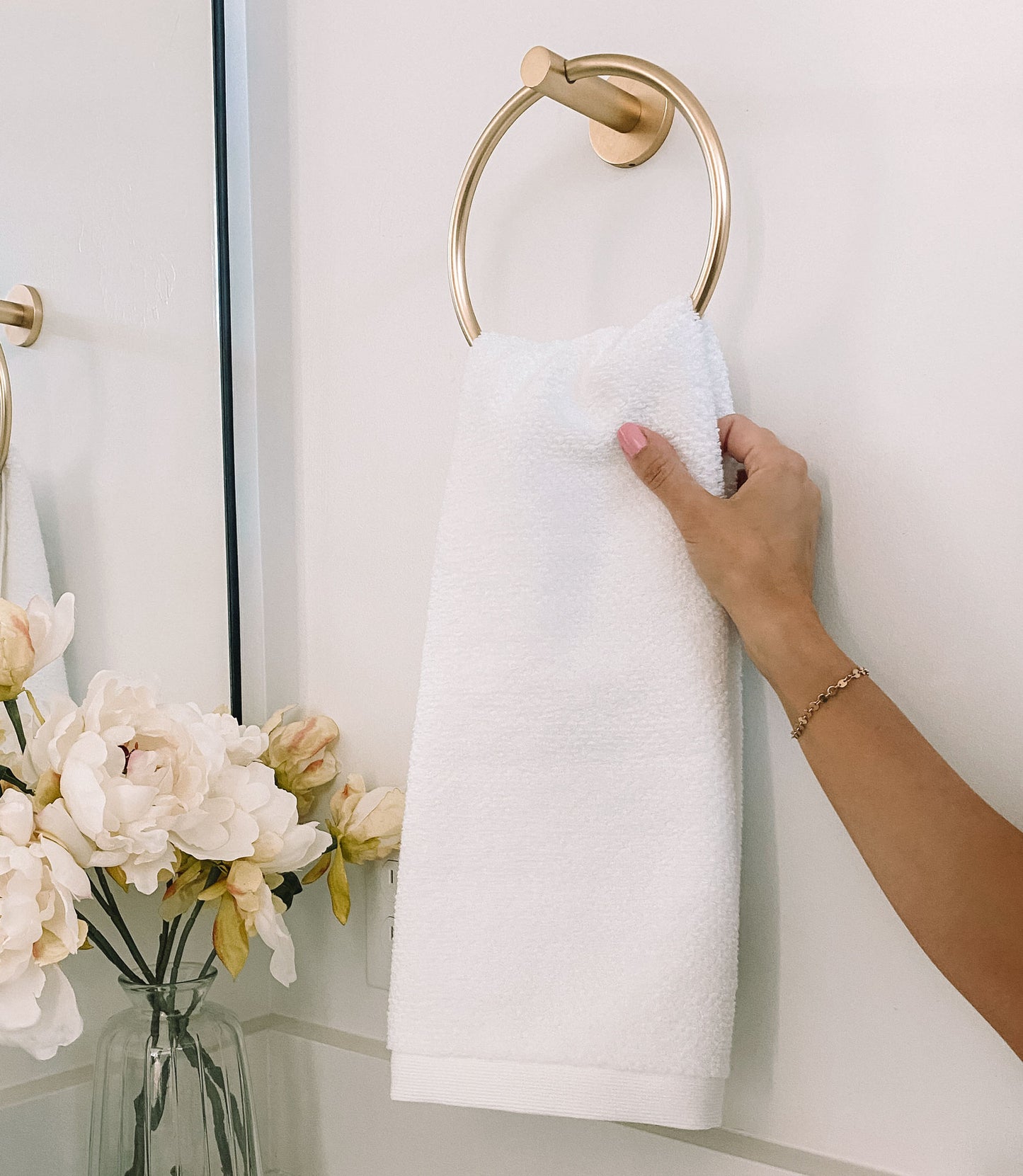 Jubilee Textured Bath Towel hanging on a gold towel ring, White