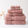 Stack of six plush, dusty rose Turkish cotton towels with a sophisticated border design on a marble surface.