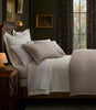 A neatly made bed in a dark, elegant bedroom featuring Savoy Jacquard Duvet and Shams.