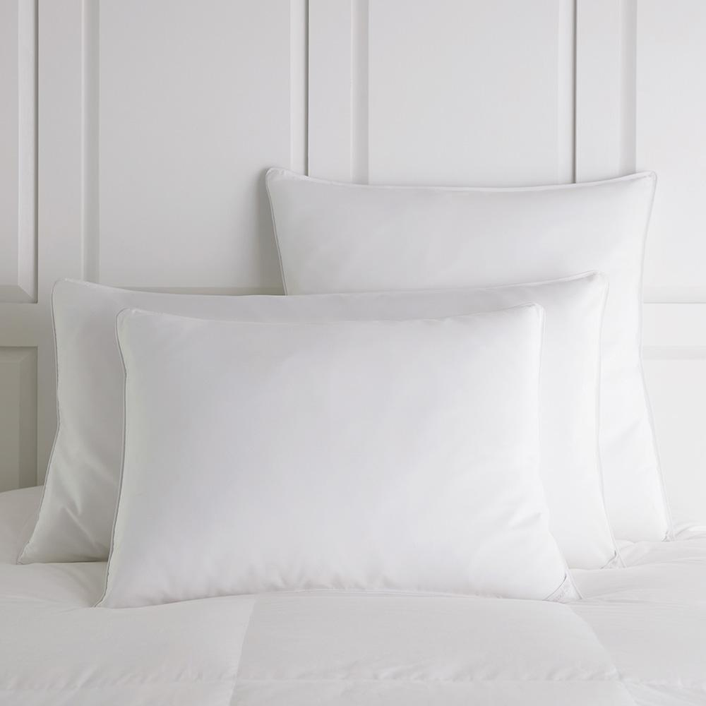Down bed pillows resting on top of a bed White