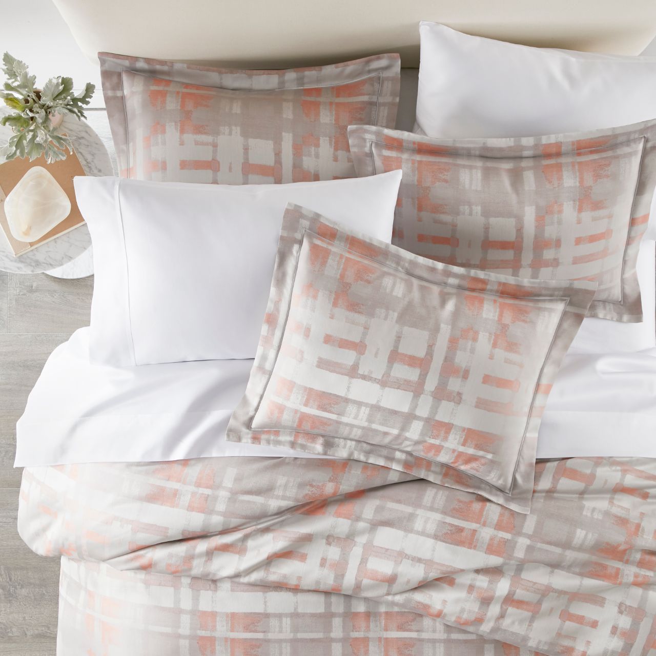 lifestyle image of Enzo shams and duvet in coral with white sheeting