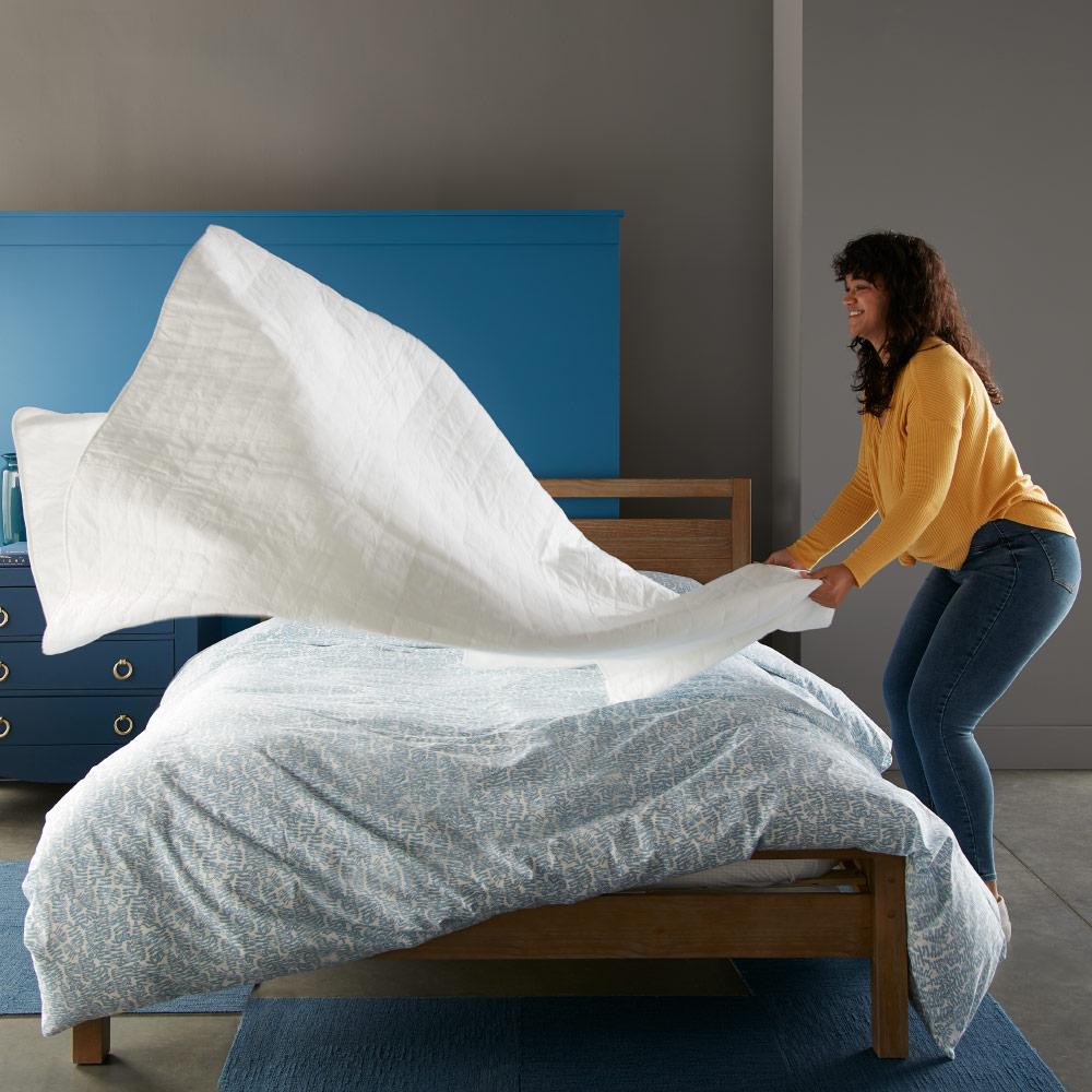 woman putting White 4 square quilted coverlet on bed