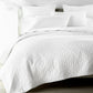 Heritage Quilt and Shams in White on Bed